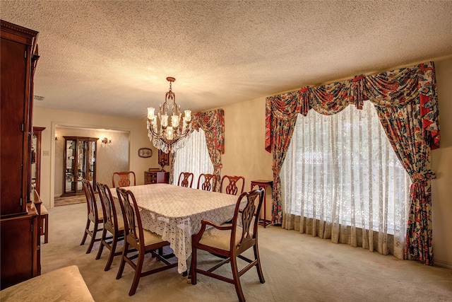 dining area featuring a textured ceiling, light colored carpet, and a notable chandelier