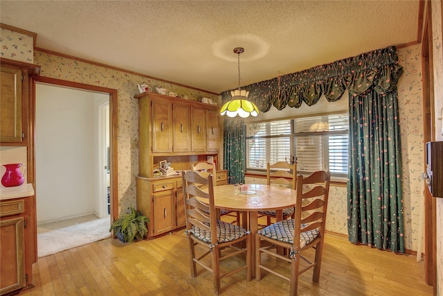 dining space with light hardwood / wood-style flooring, a textured ceiling, and crown molding