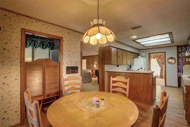 dining area with ornamental molding, a textured ceiling, and light hardwood / wood-style floors