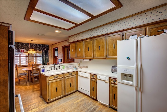 kitchen featuring light hardwood / wood-style floors, sink, kitchen peninsula, white appliances, and decorative light fixtures