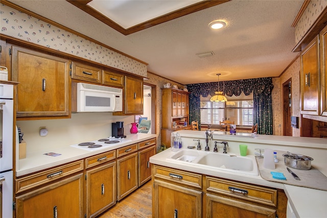 kitchen with white appliances, pendant lighting, a textured ceiling, light wood-type flooring, and sink