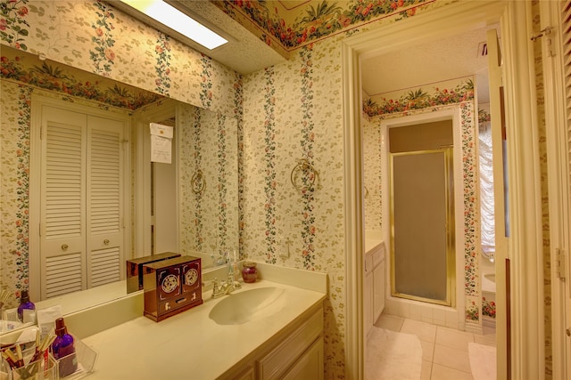 bathroom featuring vanity, a textured ceiling, a shower with door, and tile patterned floors