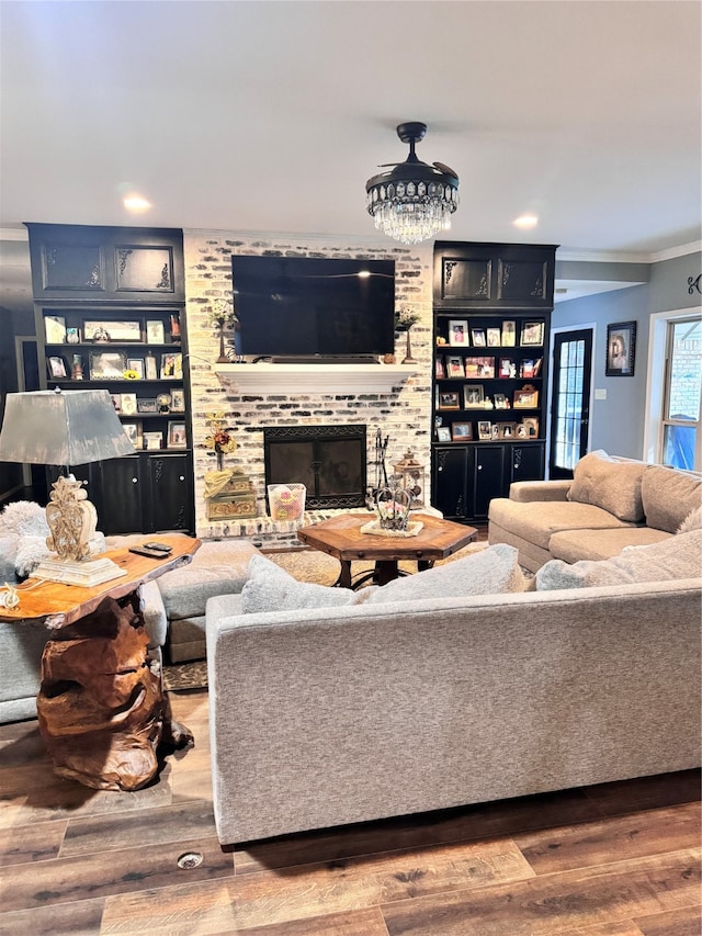 living room with a brick fireplace, hardwood / wood-style floors, and crown molding