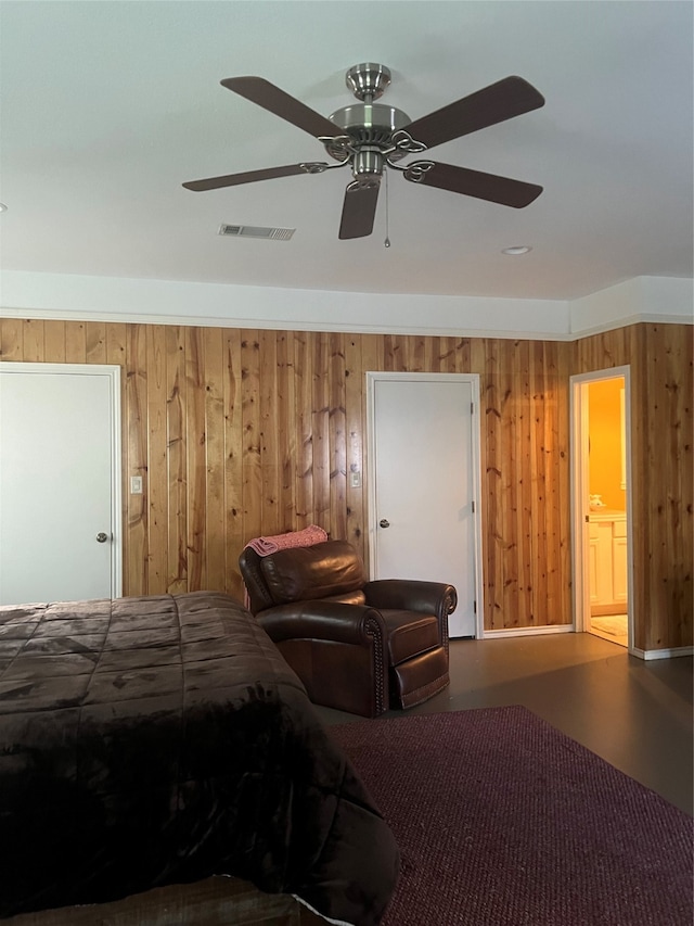 bedroom with wooden walls, ensuite bath, and ceiling fan