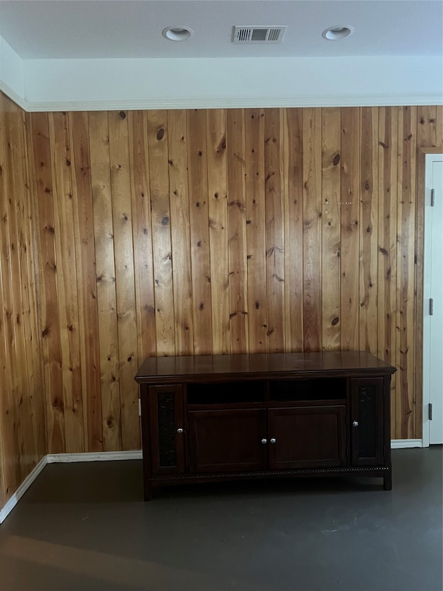 interior space featuring wooden walls and concrete flooring