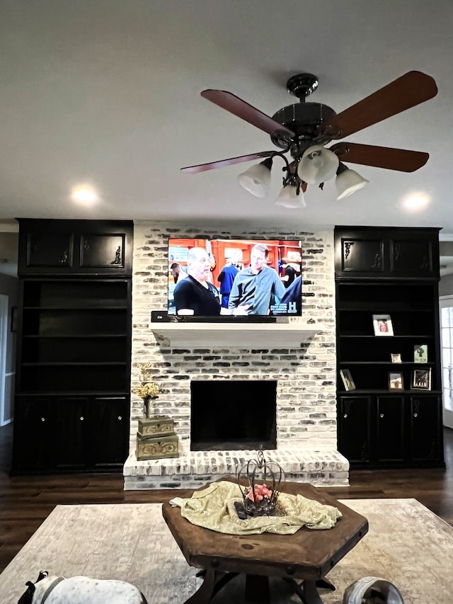 living room with a fireplace, dark hardwood / wood-style flooring, ceiling fan, and built in features