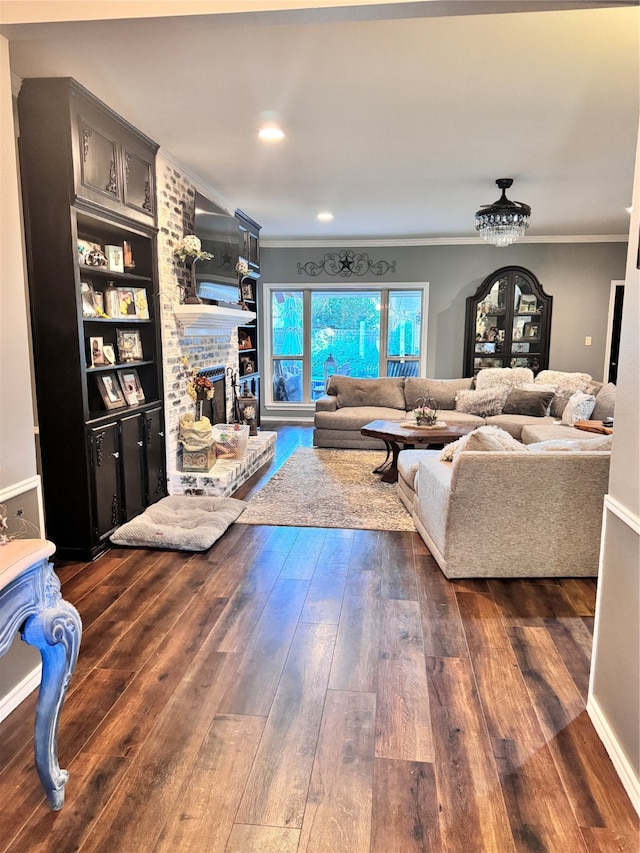 living room featuring crown molding, dark hardwood / wood-style flooring, built in features, and a brick fireplace