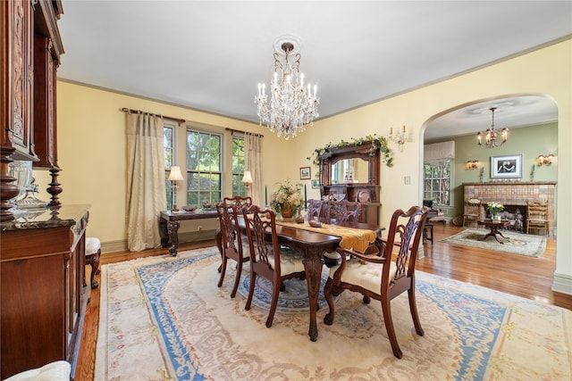 dining room with an inviting chandelier, light wood-type flooring, a fireplace, and crown molding