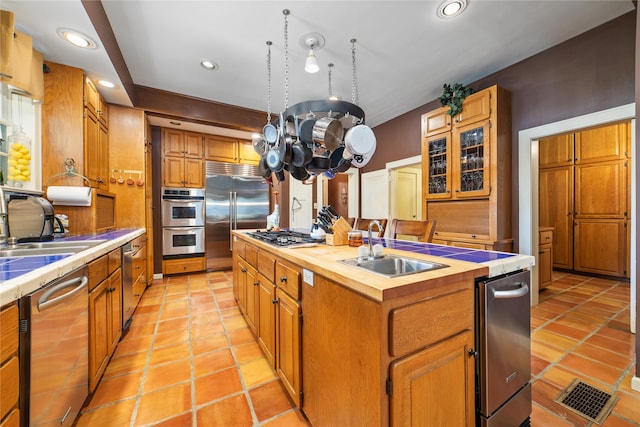 kitchen featuring tile counters, sink, an island with sink, stainless steel appliances, and light tile patterned floors