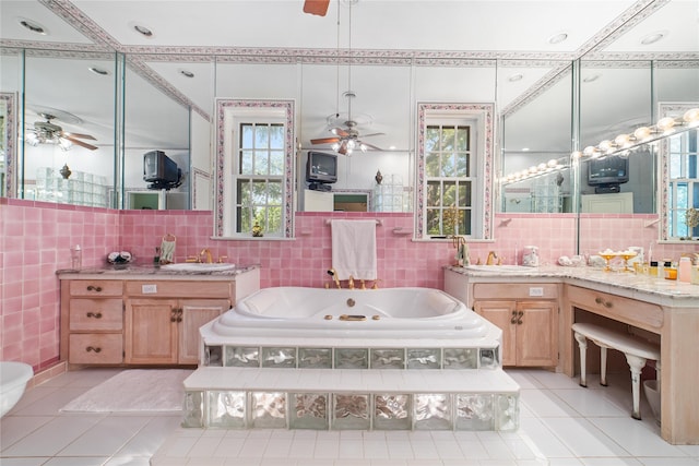 bathroom featuring tile patterned flooring, tiled tub, vanity, and ceiling fan