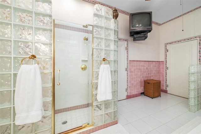 bathroom with tile walls, a shower with door, and tile patterned floors