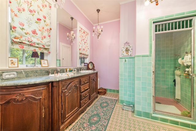 bathroom featuring tile patterned flooring, an inviting chandelier, a shower with door, ornamental molding, and vanity