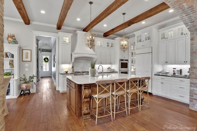 kitchen featuring a large island, backsplash, beam ceiling, and white cabinetry