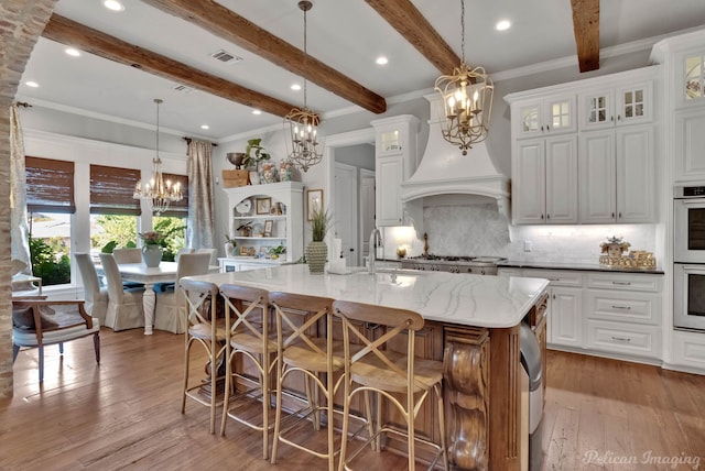 kitchen featuring beam ceiling, white cabinetry, an inviting chandelier, and a spacious island