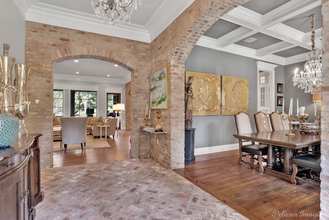 dining space featuring an inviting chandelier, coffered ceiling, ornamental molding, and hardwood / wood-style floors