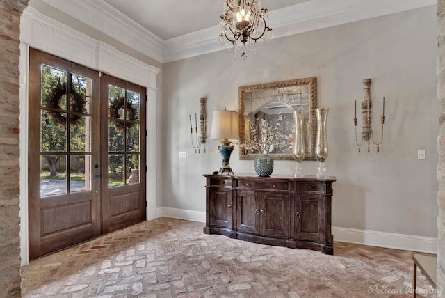 entrance foyer with ornamental molding, an inviting chandelier, and french doors