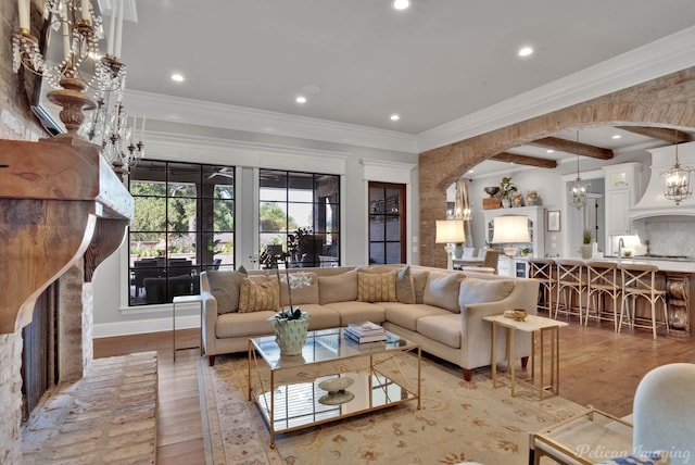 living room with ornamental molding, a notable chandelier, hardwood / wood-style floors, and beamed ceiling