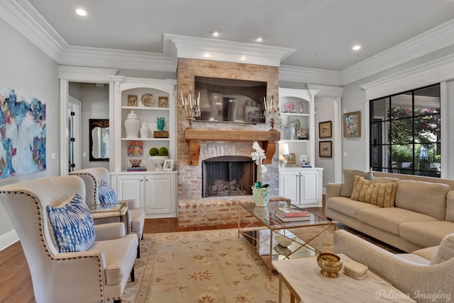 living room featuring light wood-type flooring, built in shelves, ornamental molding, and a brick fireplace