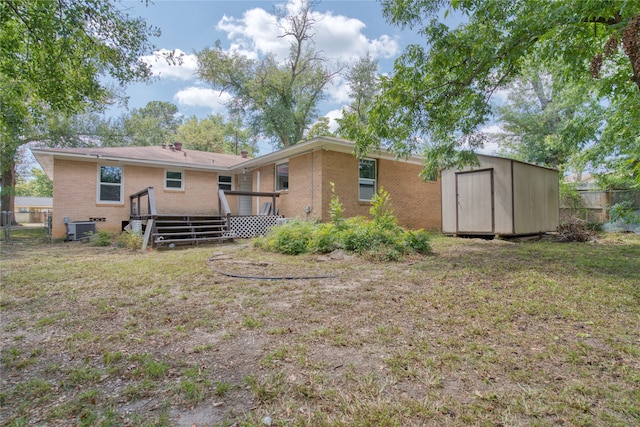 rear view of property featuring a lawn, cooling unit, a deck, and a shed