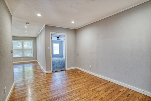 empty room with light wood-type flooring, crown molding, and ceiling fan