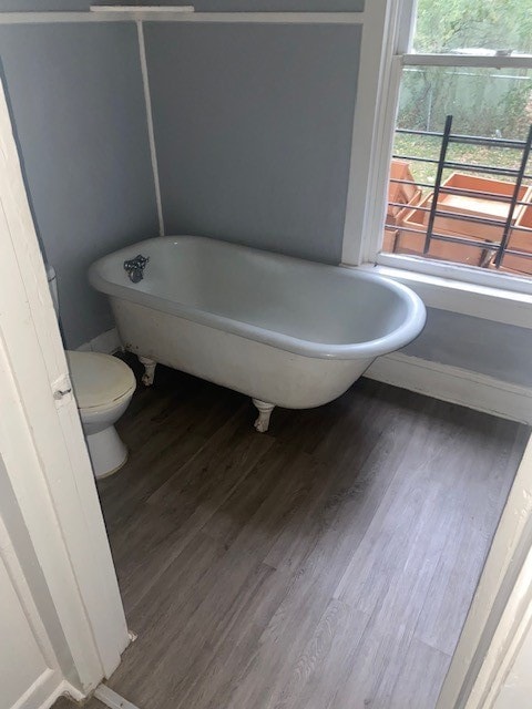 bathroom featuring hardwood / wood-style floors, toilet, and a tub