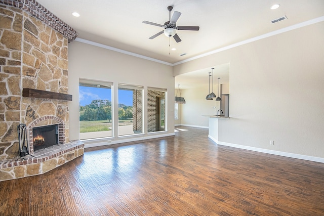 unfurnished living room featuring crown molding, a fireplace, dark hardwood / wood-style flooring, and ceiling fan