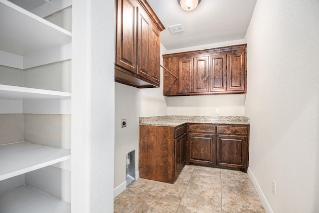 kitchen with a textured ceiling and dark brown cabinetry