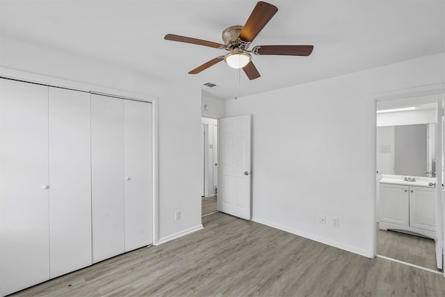 unfurnished bedroom with a closet, light wood-type flooring, connected bathroom, and ceiling fan