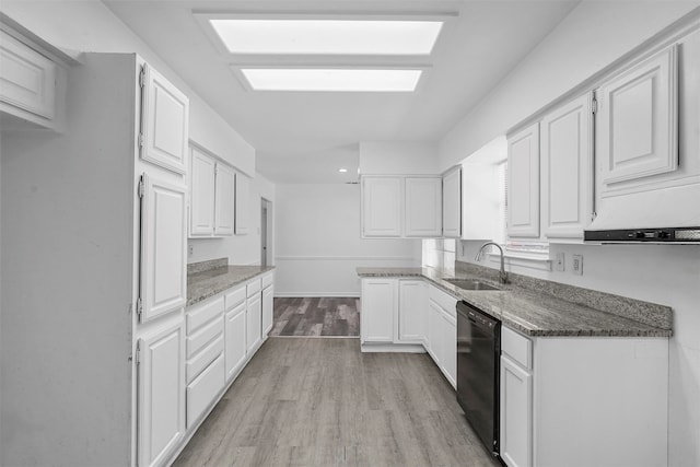 kitchen with dark stone countertops, white cabinetry, black dishwasher, light hardwood / wood-style flooring, and sink