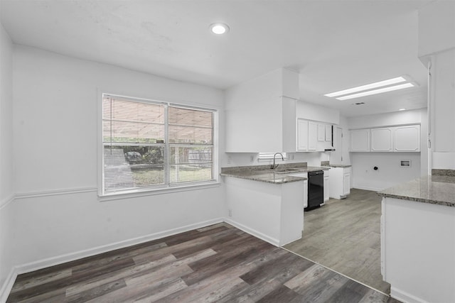 kitchen with dishwasher, sink, white cabinets, kitchen peninsula, and dark stone countertops