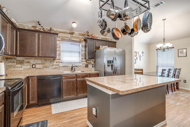 kitchen featuring a kitchen island, black appliances, an inviting chandelier, light hardwood / wood-style flooring, and sink