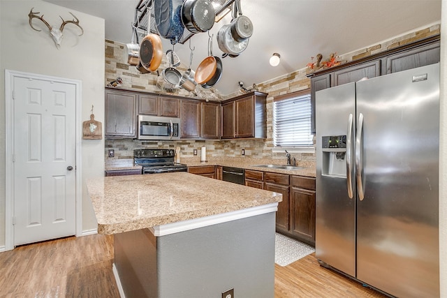 kitchen featuring a center island, sink, light hardwood / wood-style flooring, black appliances, and backsplash