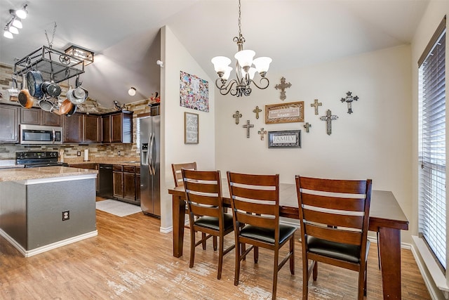 dining space featuring light wood-type flooring, lofted ceiling, and a chandelier