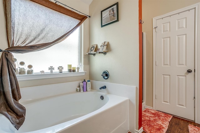 bathroom featuring wood-type flooring and a tub to relax in