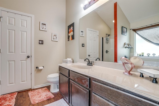 bathroom featuring a shower, vaulted ceiling, vanity, toilet, and hardwood / wood-style floors