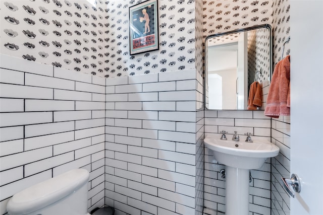 bathroom featuring tile walls and toilet