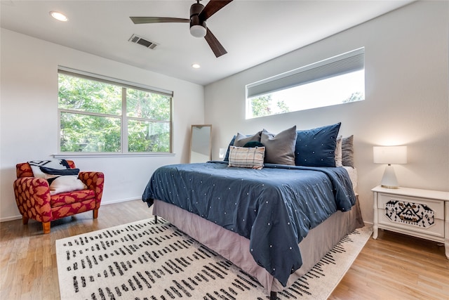 bedroom with hardwood / wood-style floors, multiple windows, and ceiling fan