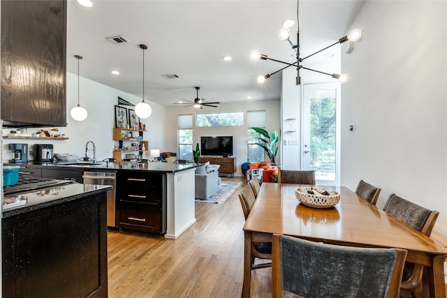 kitchen with pendant lighting, light hardwood / wood-style floors, sink, ceiling fan with notable chandelier, and stainless steel appliances