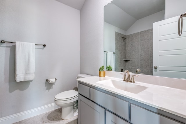 bathroom featuring vaulted ceiling, vanity, a tile shower, tile patterned flooring, and toilet