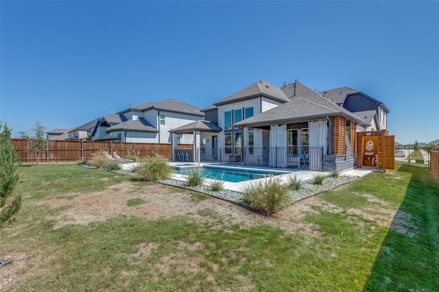 rear view of property with a fenced in pool, a lawn, and a patio area