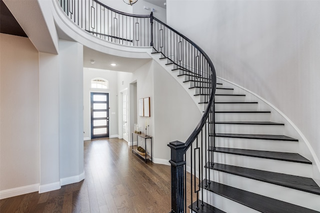 staircase with a towering ceiling and hardwood / wood-style floors