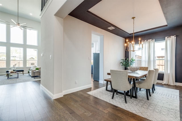 dining space featuring ceiling fan with notable chandelier, a raised ceiling, and dark hardwood / wood-style floors