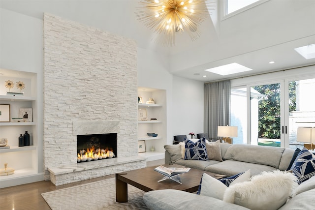 living room with hardwood / wood-style floors, built in shelves, a fireplace, and a notable chandelier