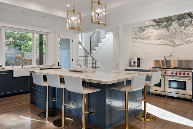 kitchen with a breakfast bar, decorative light fixtures, double oven range, and sink