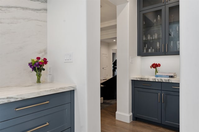 bar featuring light stone counters, dark wood-type flooring, and crown molding