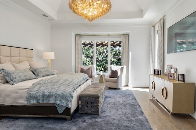 bedroom with hardwood / wood-style floors, an inviting chandelier, crown molding, and a tray ceiling