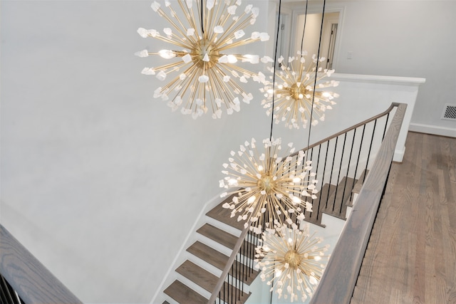 staircase with hardwood / wood-style flooring and a notable chandelier