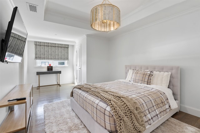 bedroom with hardwood / wood-style floors, a raised ceiling, and ornamental molding