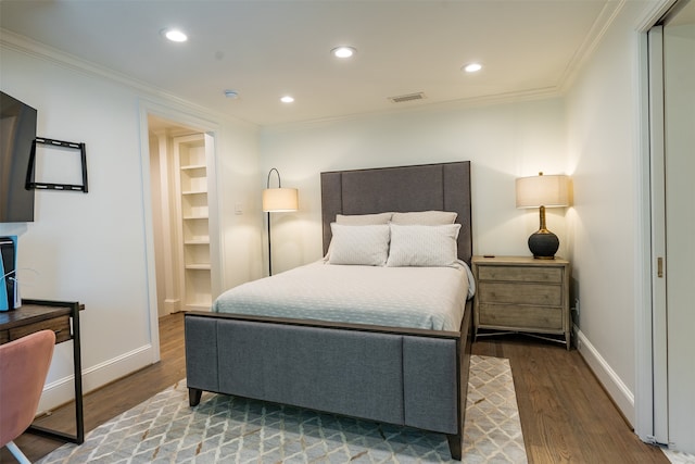 bedroom with wood-type flooring, a walk in closet, ornamental molding, and a closet