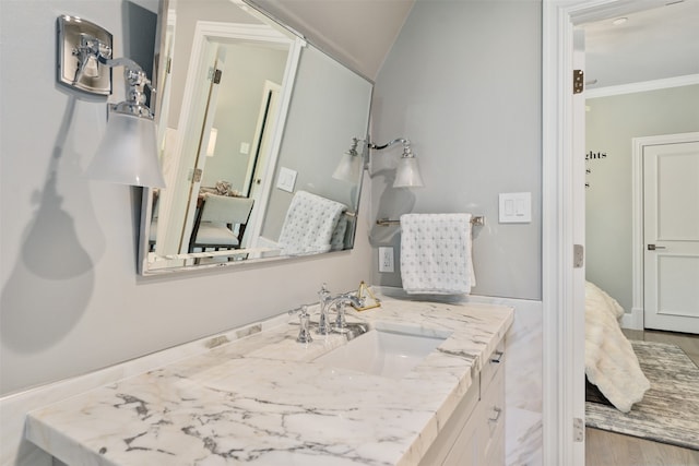 bathroom with wood-type flooring, vanity, vaulted ceiling, and ornamental molding